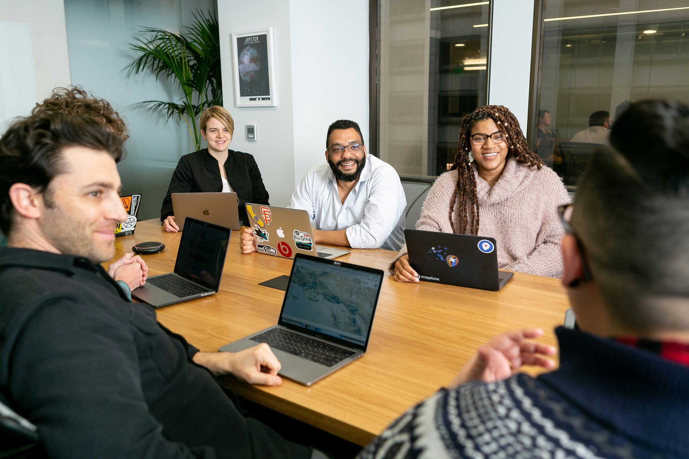 Colleagues smiling around a conference table with their laptops open